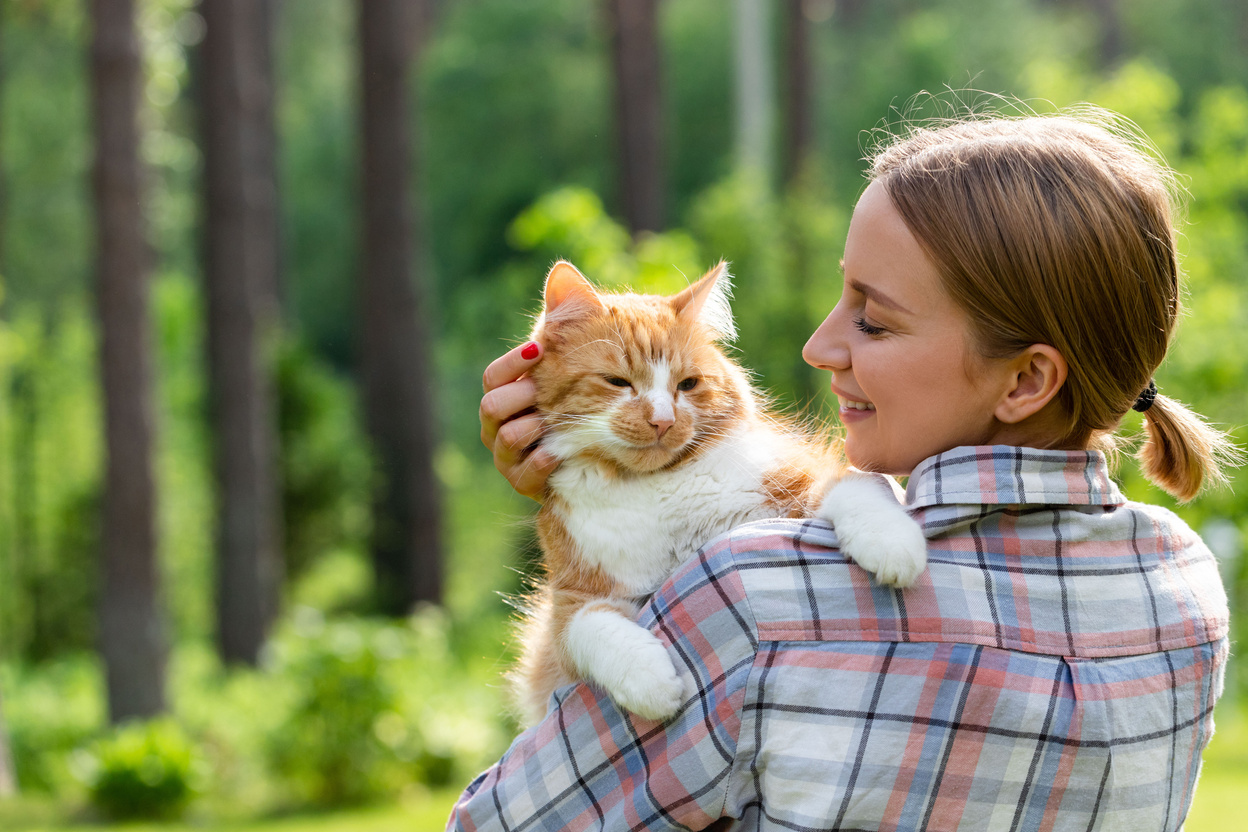 Woman in Checked Shirt Hugging Cat